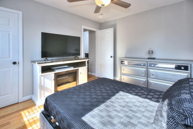 bedroom with ceiling fan, wood finished floors, and baseboards