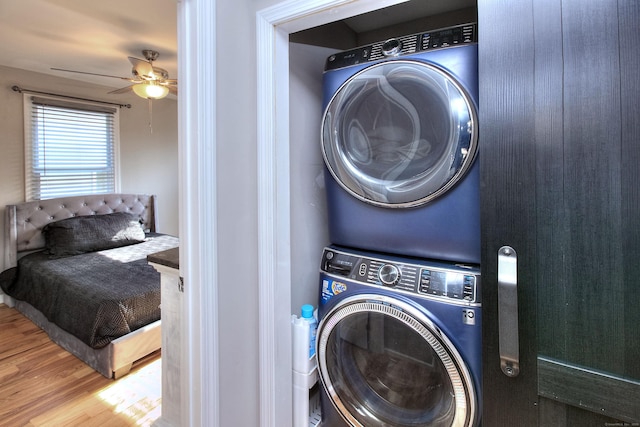 laundry area with ceiling fan, stacked washer / dryer, and wood finished floors