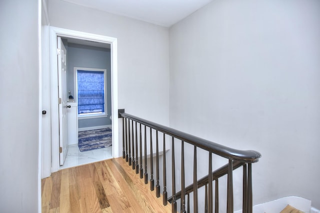 corridor with marble finish floor and an upstairs landing