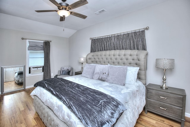 bedroom with baseboards, visible vents, lofted ceiling, wood finished floors, and cooling unit