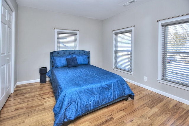 bedroom featuring light wood-type flooring, visible vents, and baseboards