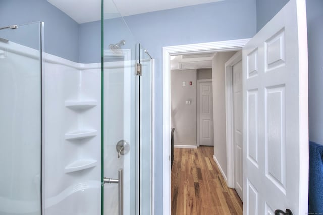 full bathroom featuring a stall shower, wood finished floors, and baseboards