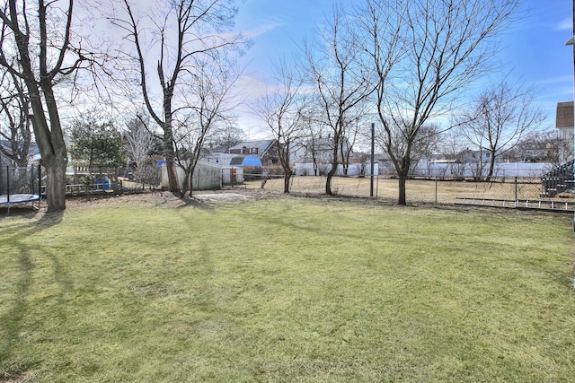 view of yard featuring a trampoline and fence