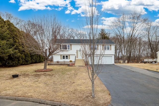 bi-level home with aphalt driveway, a front yard, a chimney, and a garage