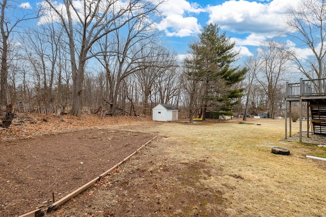 view of yard featuring an outdoor structure, a wooden deck, a storage shed, and stairs