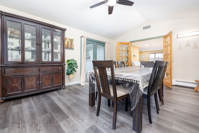 dining room with vaulted ceiling, a baseboard radiator, wood finished floors, and visible vents