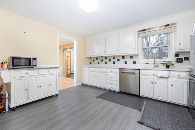 kitchen featuring stainless steel appliances, white cabinetry, and decorative backsplash