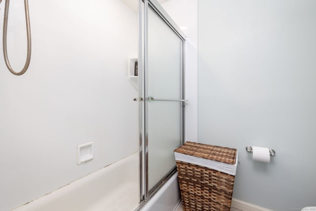 bathroom with bath / shower combo with glass door