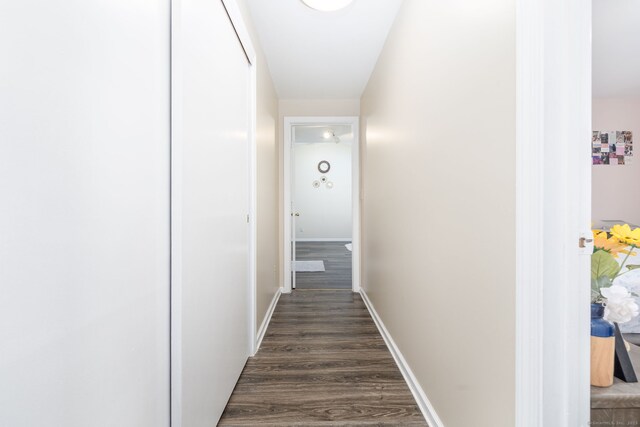 hall with dark wood-type flooring and baseboards