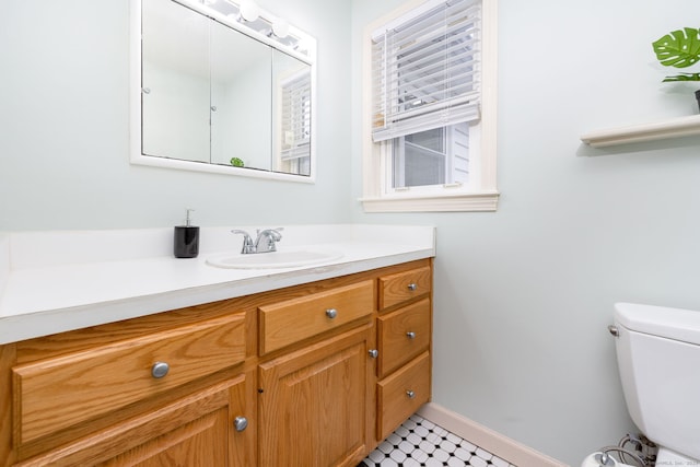 bathroom with baseboards, vanity, and toilet