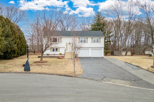 bi-level home featuring an attached garage and aphalt driveway