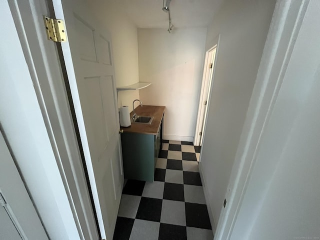 corridor featuring track lighting, a sink, and tile patterned floors