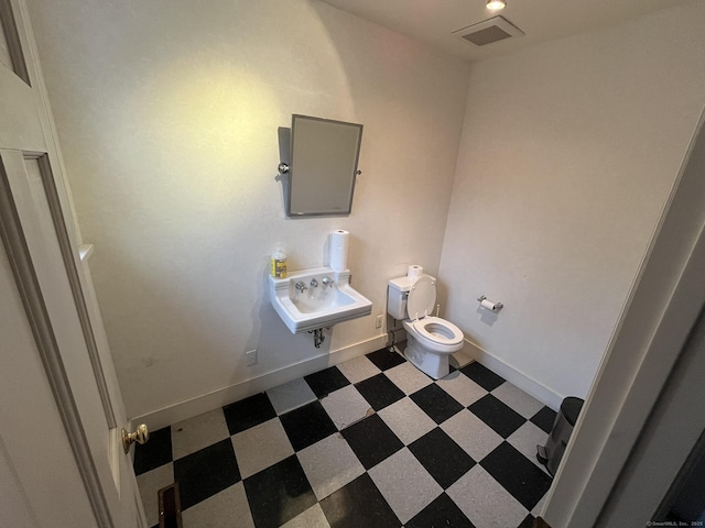 bathroom with baseboards, visible vents, toilet, tile patterned floors, and a sink