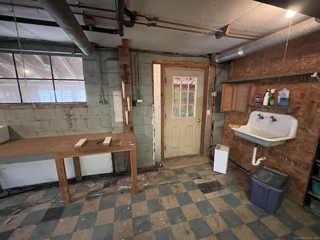 below grade area featuring concrete block wall, a sink, and tile patterned floors