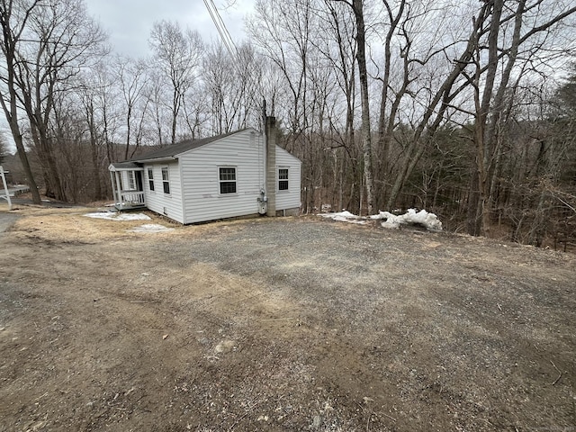 view of side of property with a chimney and dirt driveway