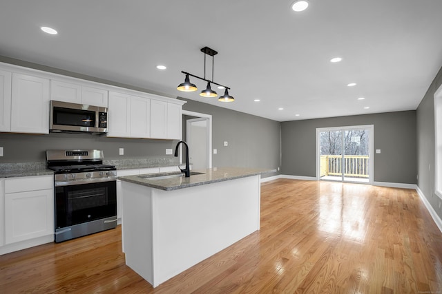 kitchen with stainless steel appliances, light wood-type flooring, a sink, and white cabinetry