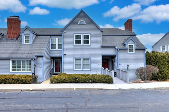 view of front of house with a shingled roof and a chimney