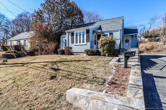 view of front of property with roof with shingles and a front lawn