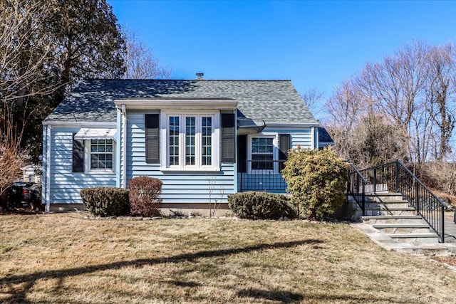 view of front facade featuring a front yard and a shingled roof