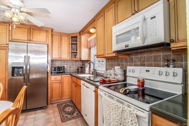 kitchen featuring a sink, white appliances, tasteful backsplash, and brown cabinetry