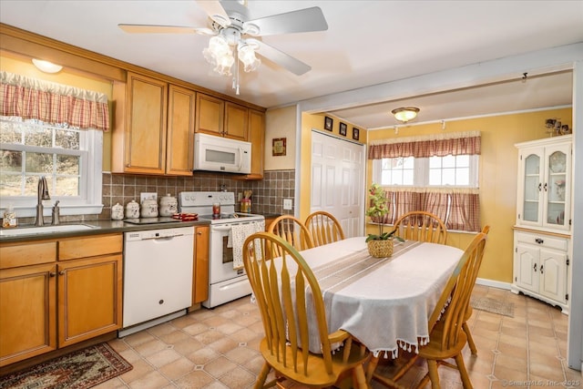 kitchen with a sink, dark countertops, white appliances, brown cabinetry, and decorative backsplash