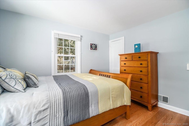 bedroom with visible vents, baseboards, and wood finished floors