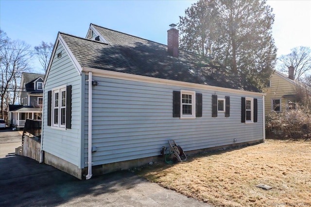 view of side of home with a chimney and a shingled roof