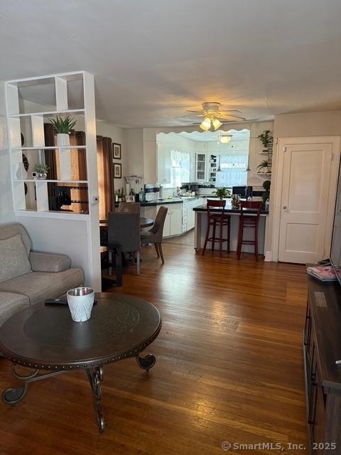 living area with wood finished floors and ceiling fan