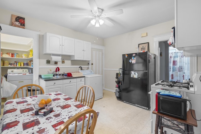 kitchen with light floors, washer / clothes dryer, freestanding refrigerator, and white cabinets