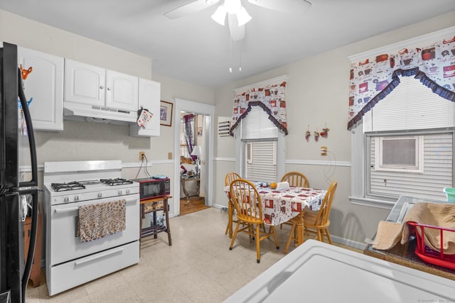 interior space featuring light floors, white gas range, freestanding refrigerator, white cabinetry, and under cabinet range hood