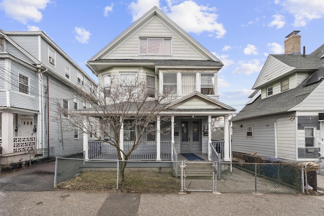 view of front facade with covered porch, a fenced front yard, and a gate