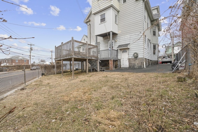 rear view of property with a yard, fence, a deck, and stairs