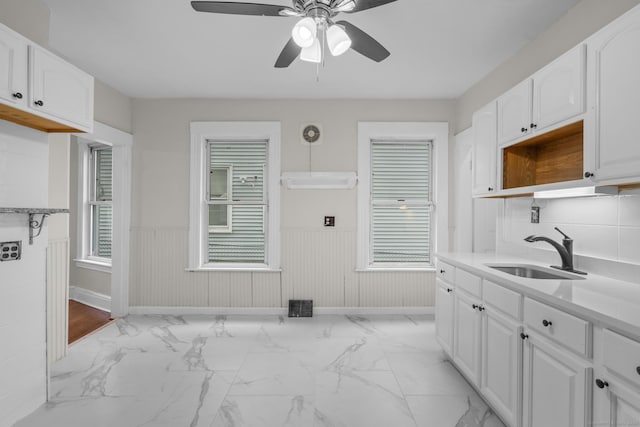 kitchen with white cabinets, wainscoting, and a sink