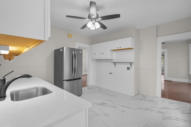 kitchen featuring freestanding refrigerator, marble finish floor, a wainscoted wall, and a sink