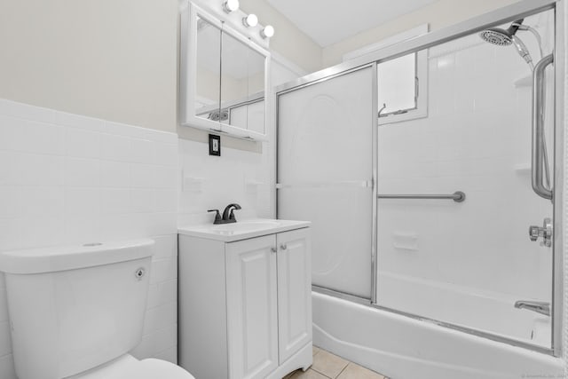 full bath featuring tile patterned flooring, toilet, bath / shower combo with glass door, vanity, and tile walls