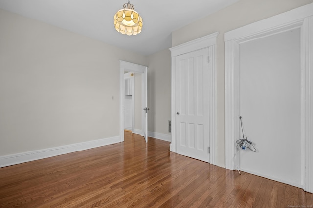 unfurnished bedroom featuring a closet, wood finished floors, and baseboards