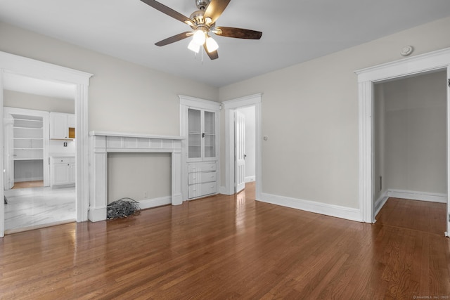 unfurnished living room featuring a ceiling fan, a fireplace, baseboards, and wood finished floors