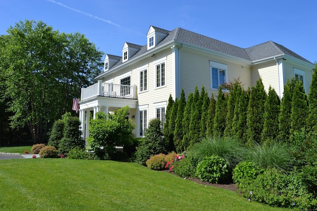 view of property exterior with a lawn, roof with shingles, and a balcony