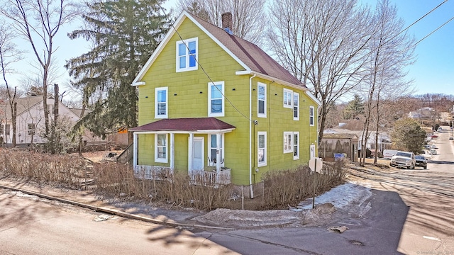 view of front of property featuring a chimney and a shingled roof