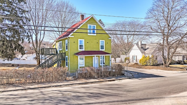 view of front of house with stairs, fence, and a chimney