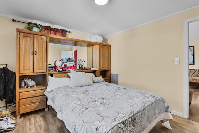 bedroom featuring wood finished floors, baseboards, and ornamental molding