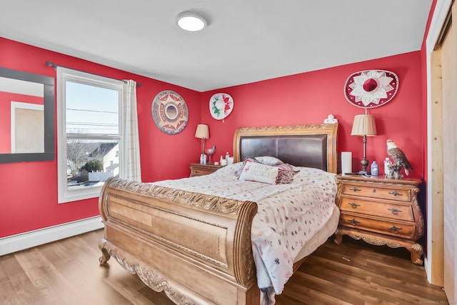 bedroom featuring wood finished floors, baseboards, and a baseboard radiator