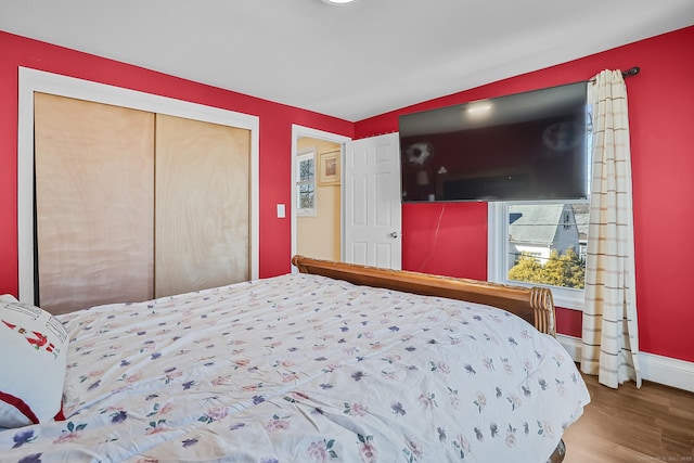 bedroom with wood finished floors, a closet, and baseboards