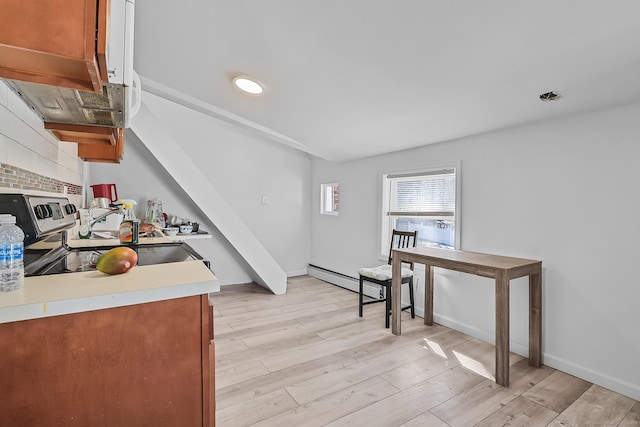 kitchen featuring tasteful backsplash, light wood finished floors, light countertops, electric range oven, and brown cabinets