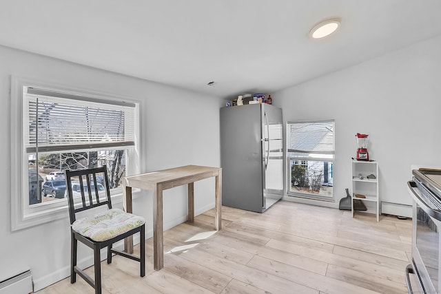 kitchen with light wood finished floors, stainless steel appliances, a baseboard heating unit, and baseboards