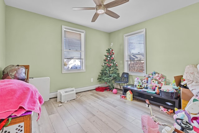 bedroom featuring baseboards, a baseboard heating unit, a ceiling fan, and wood finished floors