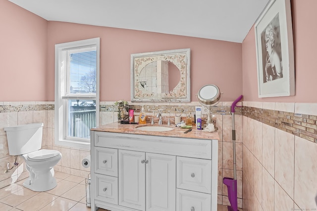 bathroom with tile patterned floors, toilet, tile walls, vanity, and vaulted ceiling