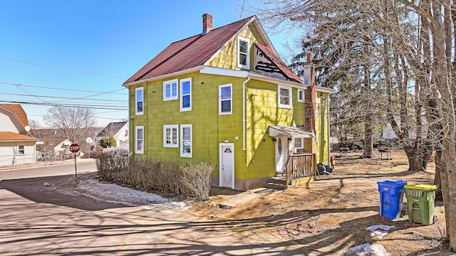 view of property exterior featuring roof with shingles and a chimney