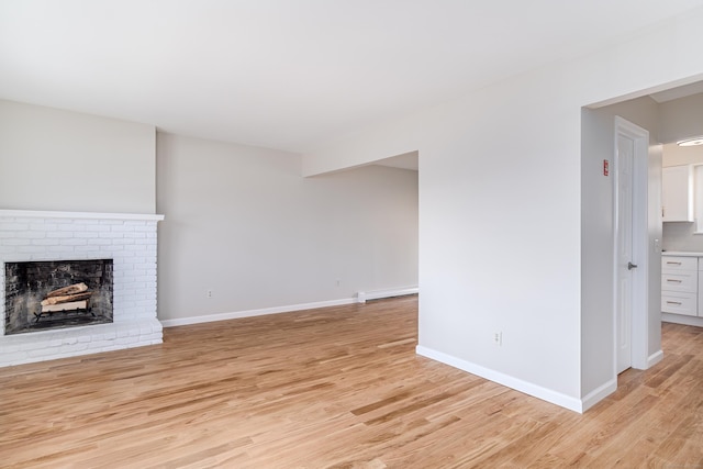 unfurnished living room with a baseboard radiator, a fireplace, light wood-style flooring, and baseboards