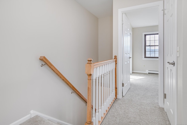 hallway featuring baseboards, a baseboard heating unit, carpet flooring, and an upstairs landing